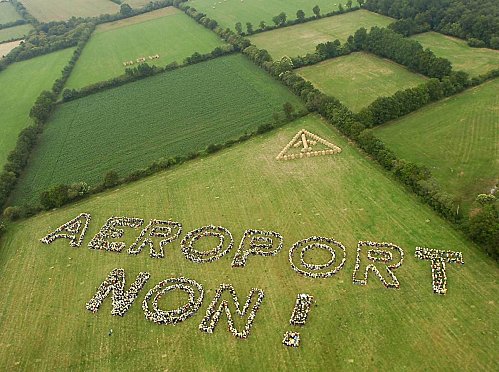 Vue aérienne de parcelles bocagères avec l'inscription "Aéroport non !" réalisée grâce à une fresque humaine.