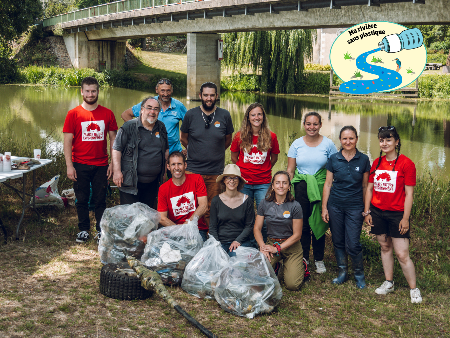 groupe de personnes blanches devant une rivière avec des sacs poubelles remplis des déchets ramassés