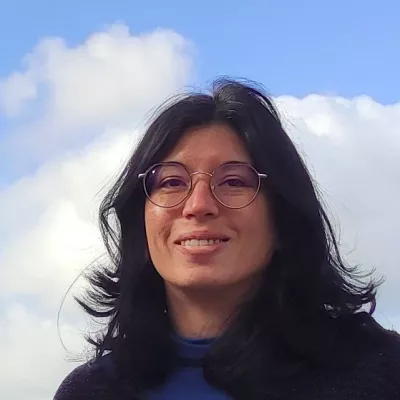 Photo portrait d'Aurélie debout avec un ciel bleu et nuageux derrière