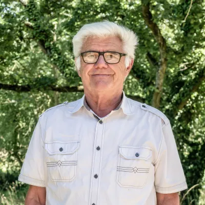 homme blanc à lunette cheveux blancs arrière plan boisé