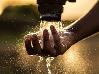 main sous un robinet d'eau dans la lumière du soleil 