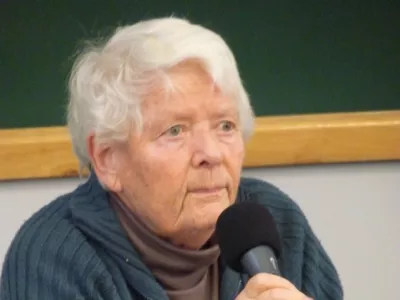 femme blanche agées cheveux courts devant un micro